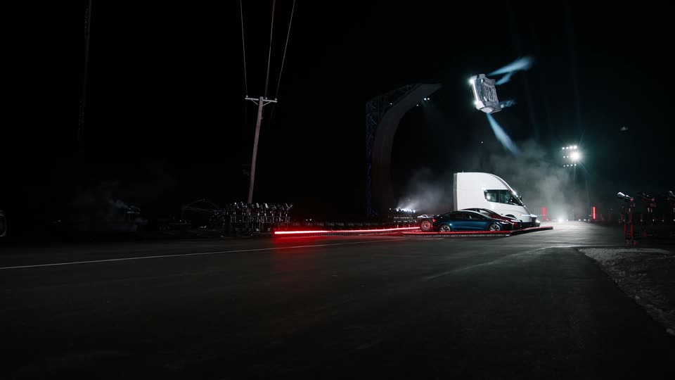 Rear angle: the car rolling high near the pole, the curved ramp of the live stunt in the background.